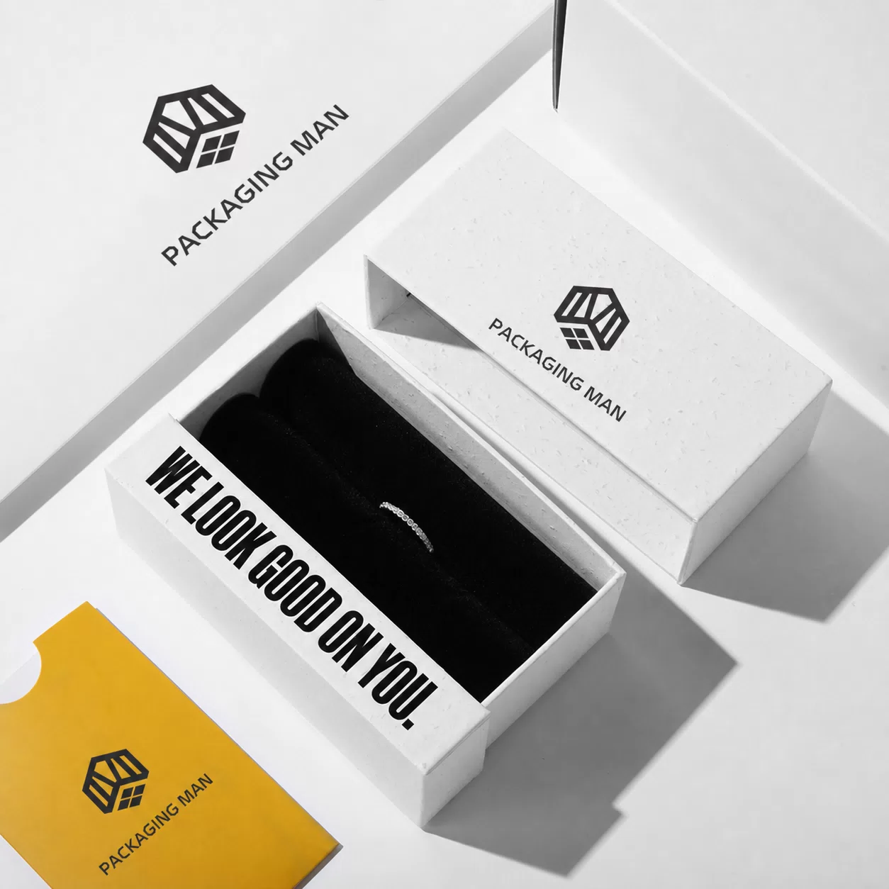 A high-angle view of the open white box with a black insert, accompanied by a yellow card placed in the foreground.