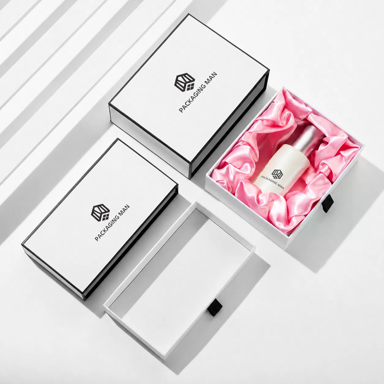 Three boxes displayed: one open with pink lining and a bottle, one empty open base, and one closed lid.