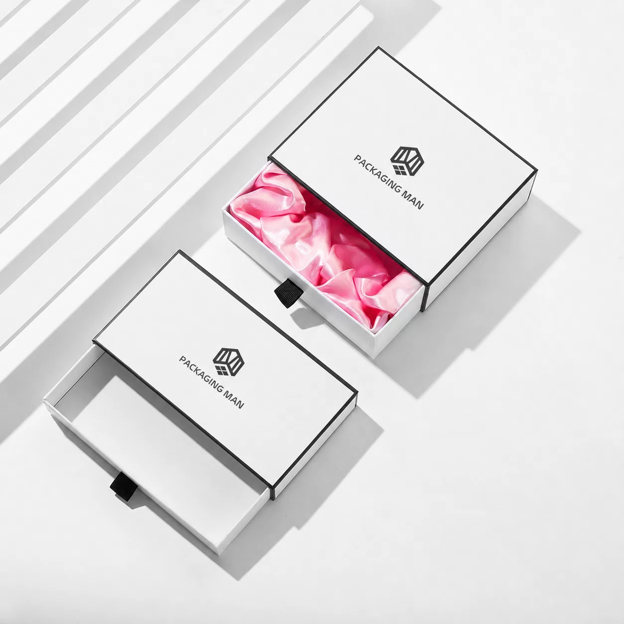 Two boxes shown partially open; the top one reveals pink satin filling while the bottom one shows an empty interior.